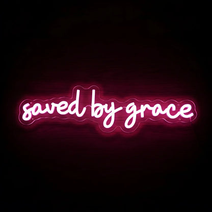 Saved by Grace LED neon sign with bright pink illumination on precision-cut acrylic backing, Christian wall decor featuring an inspirational faith message.
