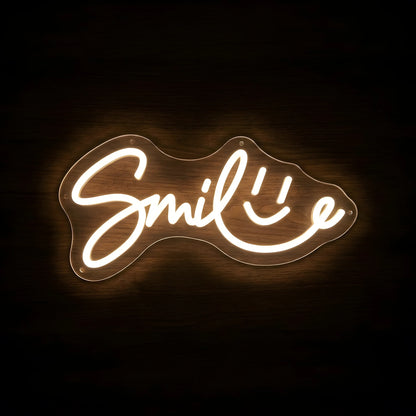 Smile Wordmark LED neon sign featuring elegant warm white Smile script lettering with an integrated smiley face on clear acrylic backing for dental clinic and cosmetic dentistry wall decor.