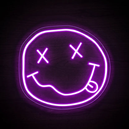 Smiley Face LED neon sign with X-shaped eyes, curved smile and tongue detail in bright purple-pink neon on clear acrylic backing.
