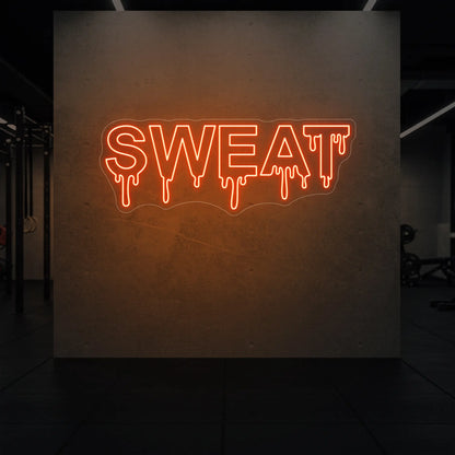 'SWEAT' neon sign glowing in golden yellow against a styled interior wall.