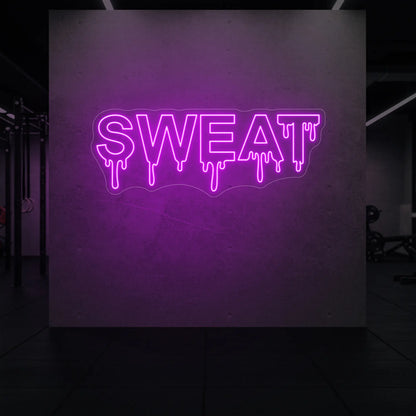 'SWEAT' neon sign glowing in deep pink against a styled interior wall.