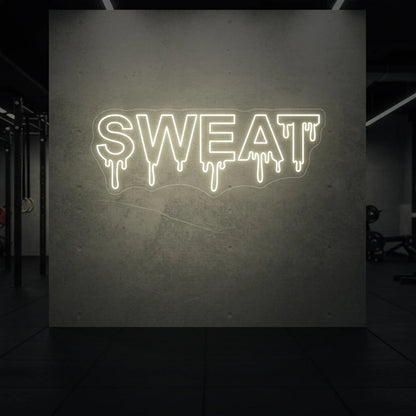'SWEAT' neon sign glowing in warm white against a styled interior wall.