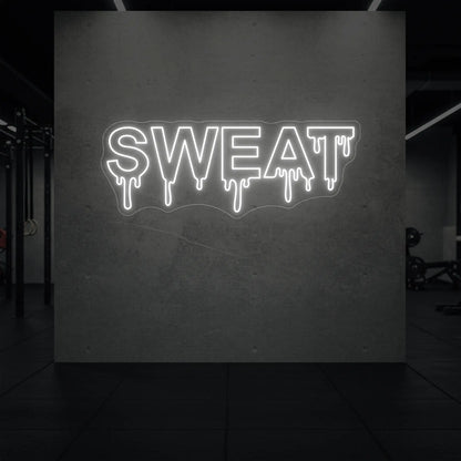 'SWEAT' neon sign glowing in cool white against a styled interior wall.