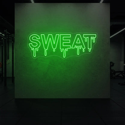 'SWEAT' neon sign glowing in green against a styled interior wall.