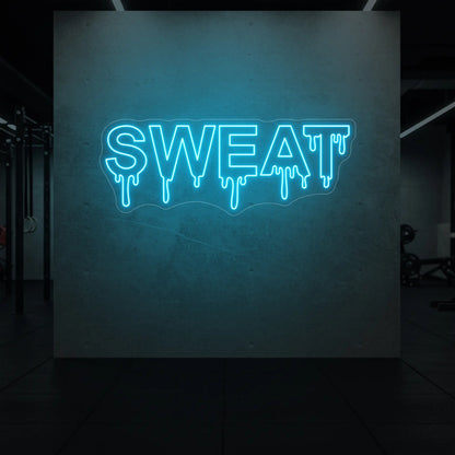 'SWEAT' neon sign glowing in ice blue against a styled interior wall.
