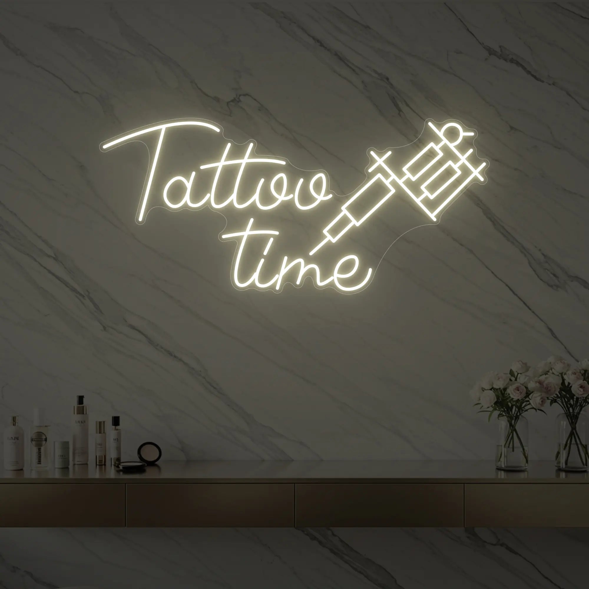 Photo of the 'Tattoo Time' neon sign glowing in warm white against a styled interior wall.