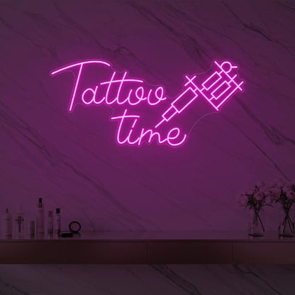 Photo of the 'Tattoo Time' neon sign glowing in light pink against a styled interior wall.