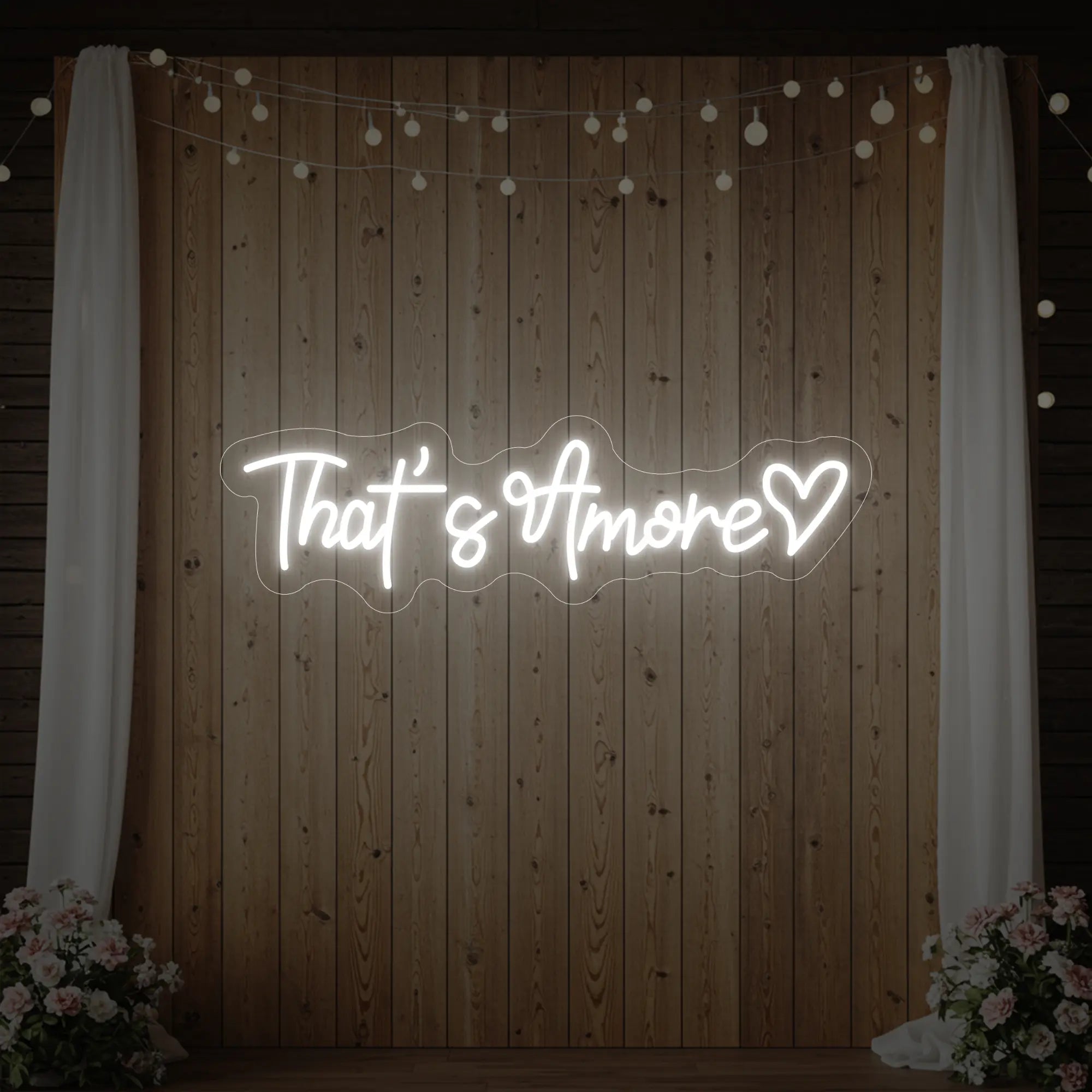 Photo of the 'That's Amore with Heart' neon sign glowing in cool white against a styled interior wall.