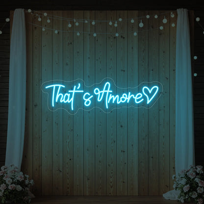 Photo of the 'That's Amore with Heart' neon sign glowing in ice blue against a styled interior wall.
