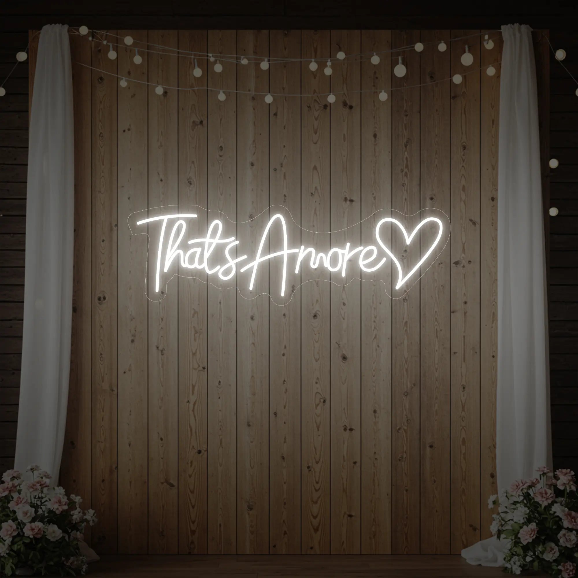 Photo of the 'That's Amore with Heart' neon sign glowing in cool white against a styled interior wall.