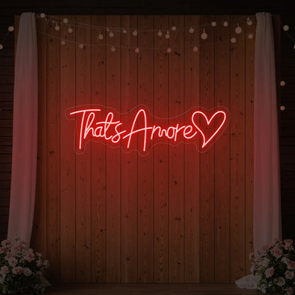 Photo of the 'That's Amore with Heart' neon sign glowing in red against a styled interior wall.