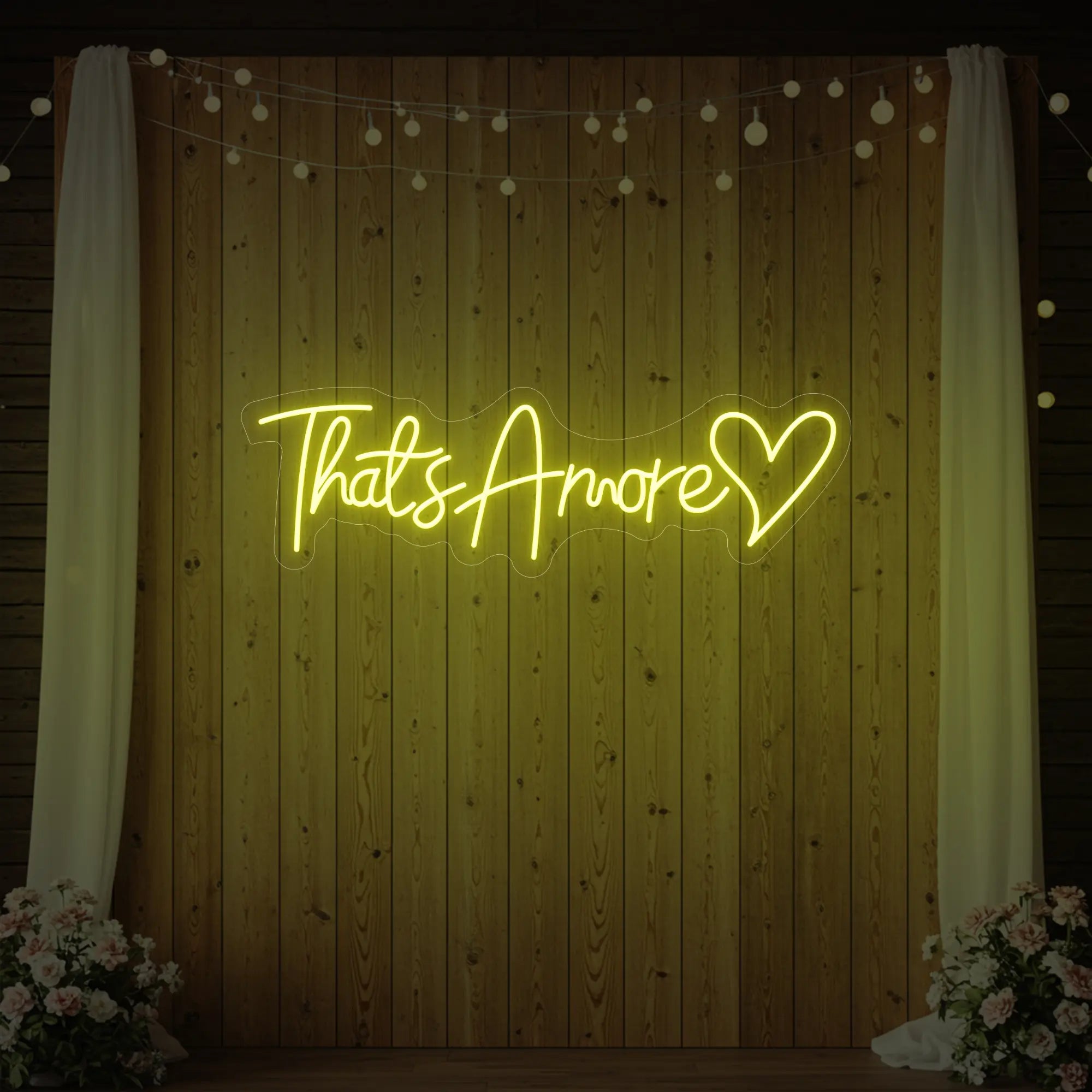 Photo of the 'That's Amore with Heart' neon sign glowing in lemon yellow against a styled interior wall.