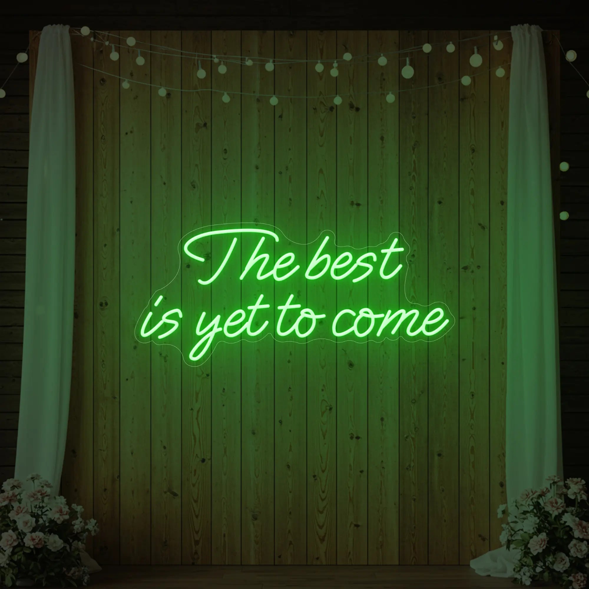  'The Best Is Yet To Come' neon sign glowing in green against a styled interior wall.