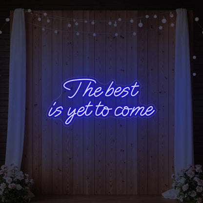 'The Best Is Yet To Come' neon sign glowing in deep blue against a styled interior wall.
