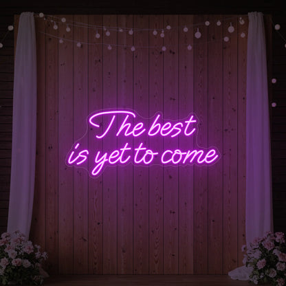 'The Best Is Yet To Come' neon sign glowing in light pink against a styled interior wall.