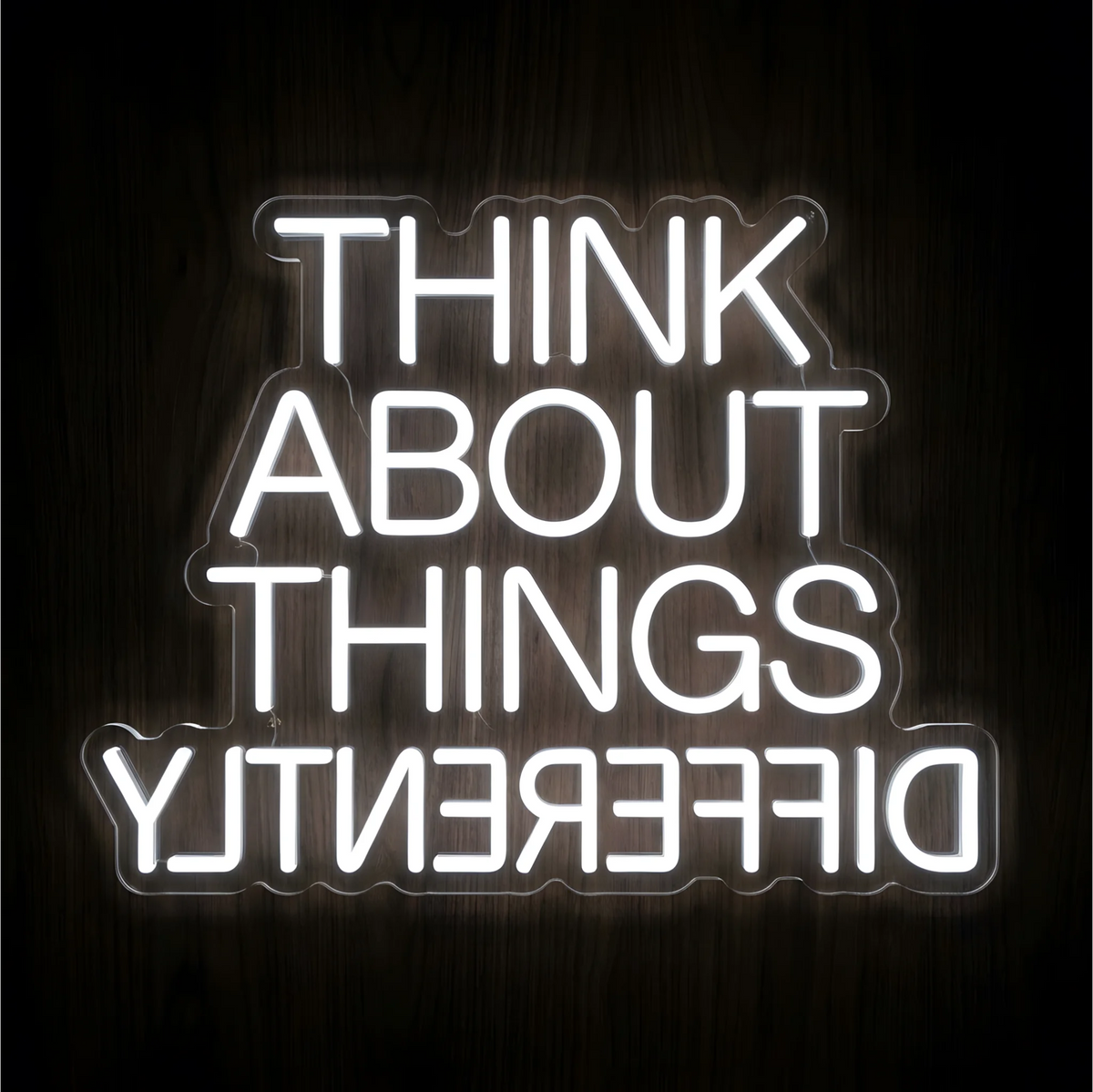 Think About Things Differently LED Neon Sign in bright white uppercase lettering on clear acrylic against a dark wood background, suited to creative studios and home offices.