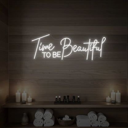Photo of the 'TIME TO BE BEAUTIFUL' neon sign glowing in cool white against a styled interior wall.