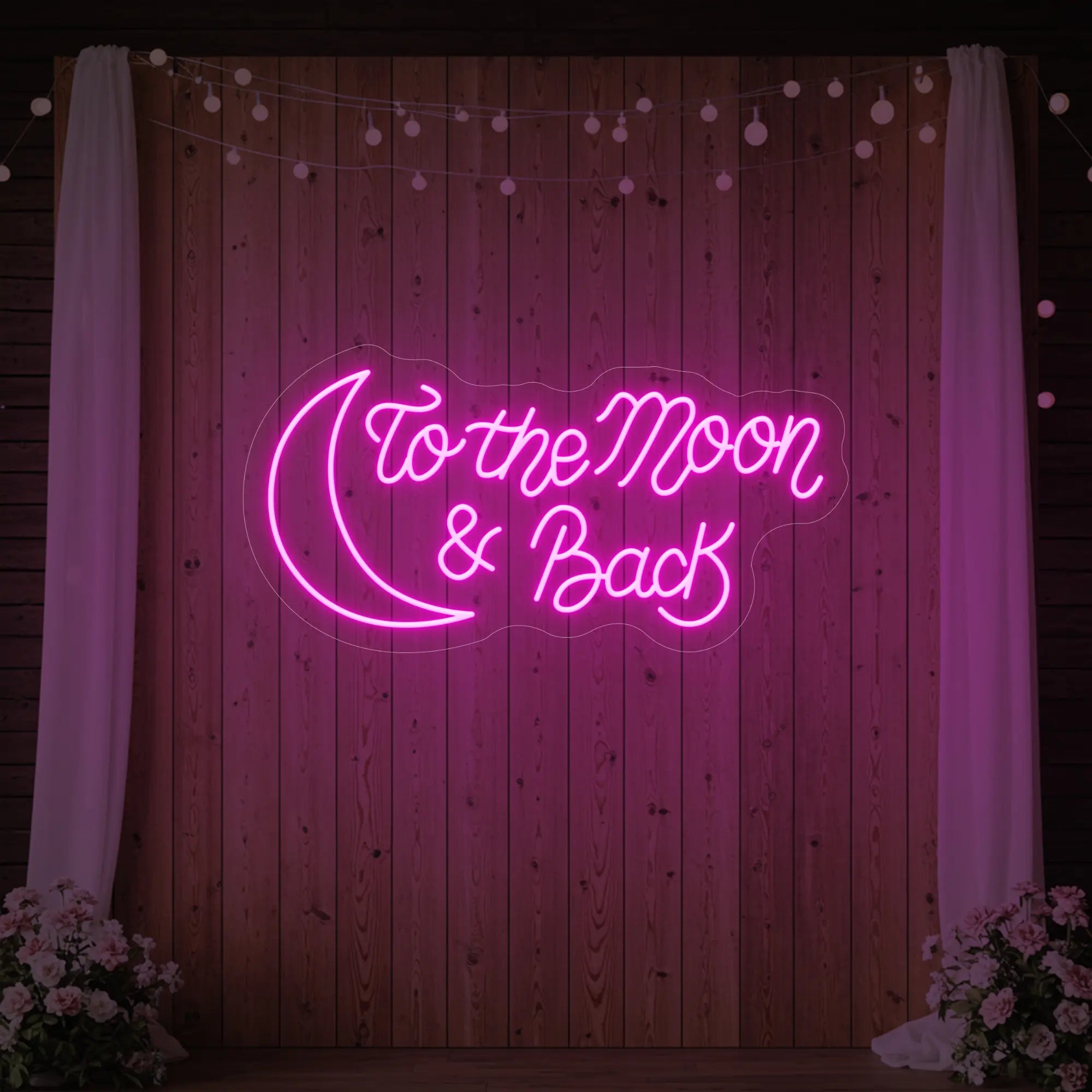  'To The Moon And Back' neon sign glowing in light pink against a styled interior wall.