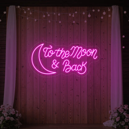  'To The Moon And Back' neon sign glowing in light pink against a styled interior wall.