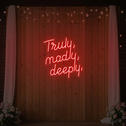  'Truly, Madly, Deeply' neon sign glowing in red against a styled interior wall.