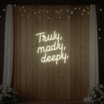  'Truly, Madly, Deeply' neon sign glowing in warm white against a styled interior wall.