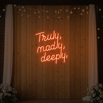  'Truly, Madly, Deeply' neon sign glowing in golden yellow against a styled interior wall.