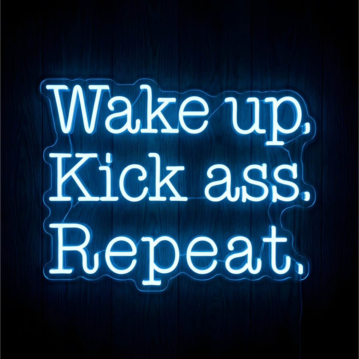 Wake Up Kick Ass Repeat LED Neon Sign displaying “Wake up, Kick ass, Repeat” in bright blue-white lettering across three lines on contoured clear acrylic backing against a dark wood background, ideal for home offices and gyms.