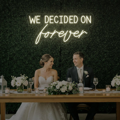  'We Decided On Forever' neon sign glowing in warm white against a styled interior wall.
