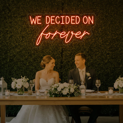  'We Decided On Forever' neon sign glowing in golden yellow against a styled interior wall.