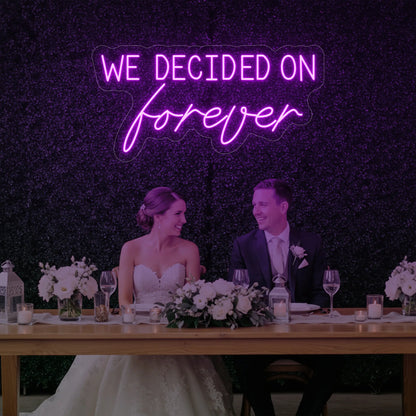  'We Decided On Forever' neon sign glowing in deep pink against a styled interior wall.