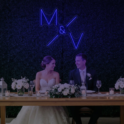 Photo of the 'Wedding Initials Custom Neon Sign V1' neon sign glowing in deep blue against a styled interior wall.
