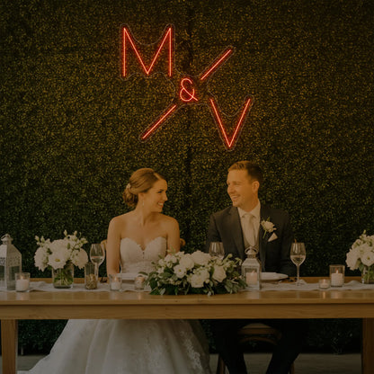 Photo of the 'Wedding Initials Custom Neon Sign V1' neon sign glowing in golden yellow against a styled interior wall.