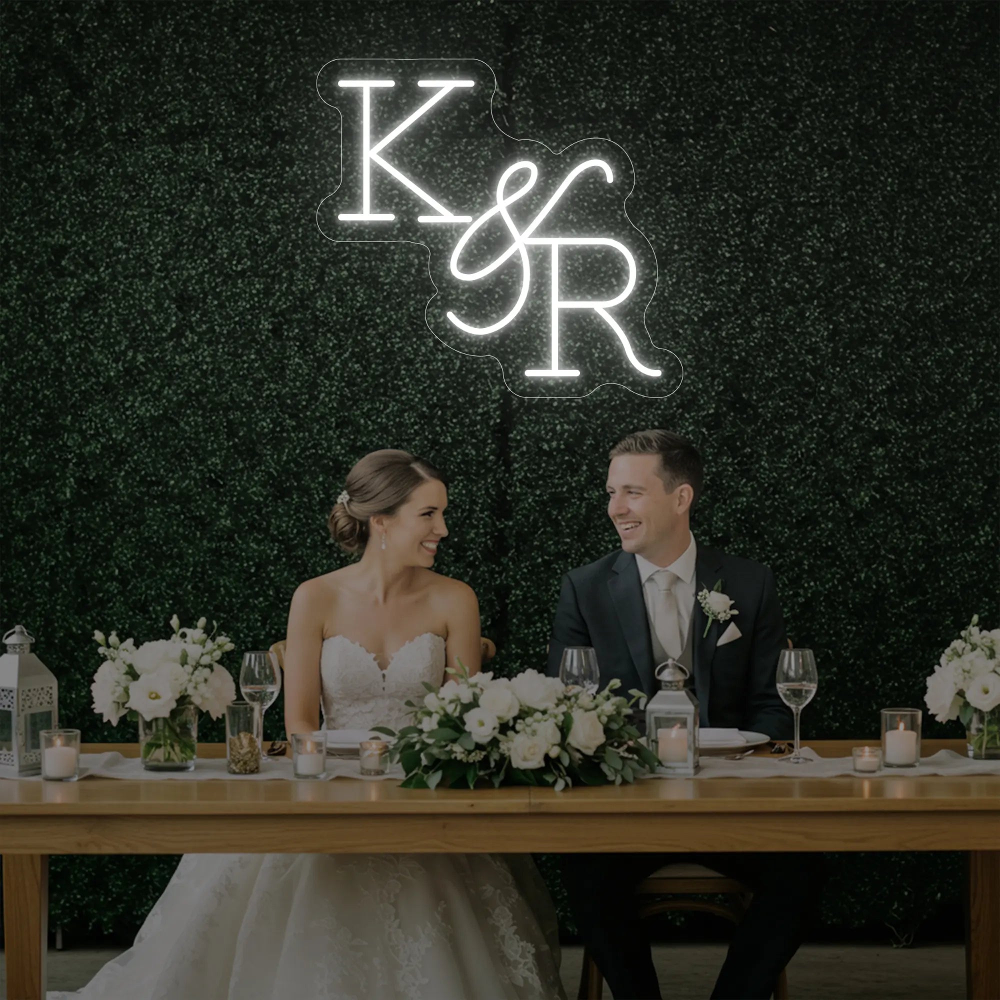Photo of the 'Wedding Initials Custom Neon Sign V2' neon sign glowing in cool white against a styled interior wall.