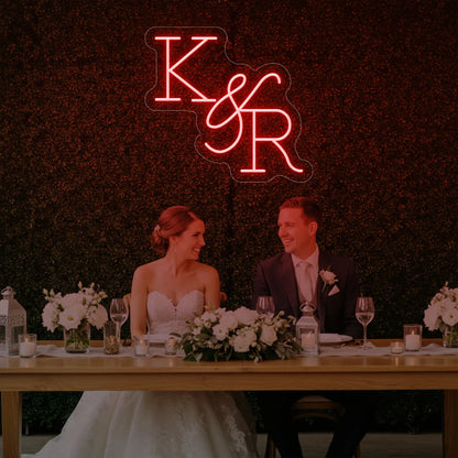 Photo of the 'Wedding Initials Custom Neon Sign V2' neon sign glowing in red against a styled interior wall.