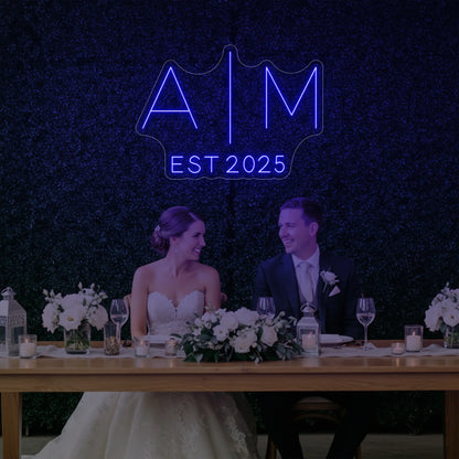 Photo of the 'Wedding Initials Custom Neon Sign V4' neon sign glowing in deep blue against a styled interior wall.