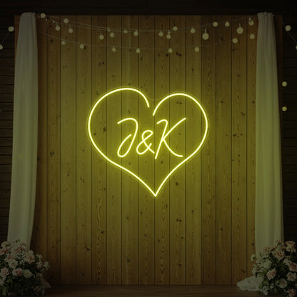 Photo of the 'Wedding Initials Custom Neon Sign V5' neon sign glowing in lemon yellow against a styled interior wall.