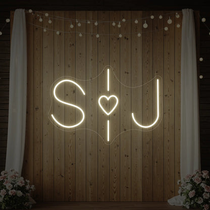 Photo of the 'Wedding Initials Custom Neon Sign V6' neon sign glowing in warm white against a styled interior wall.