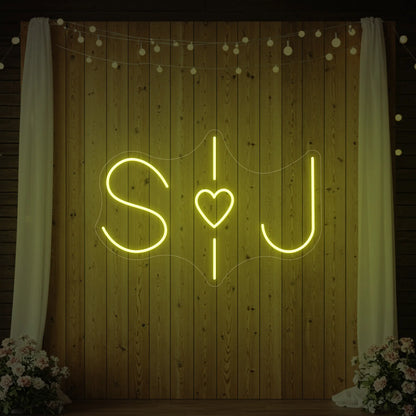 Photo of the 'Wedding Initials Custom Neon Sign V6' neon sign glowing in lemon yellow against a styled interior wall.