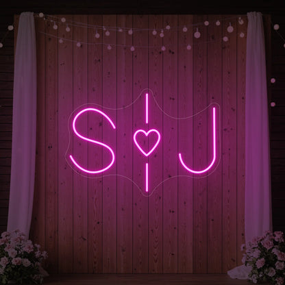 Photo of the 'Wedding Initials Custom Neon Sign V6' neon sign glowing in light pink against a styled interior wall.