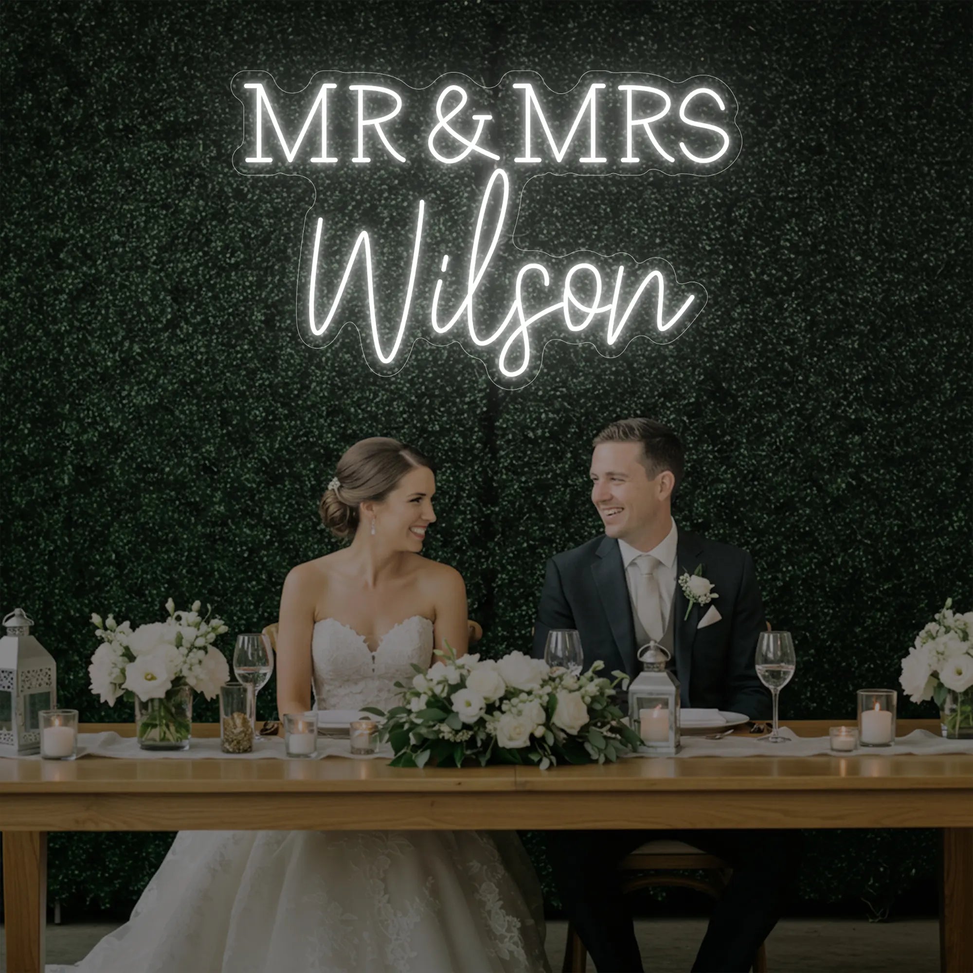 Photo of the 'Wedding Last Names Custom Neon Sign V2' neon sign glowing in cool white against a styled interior wall.