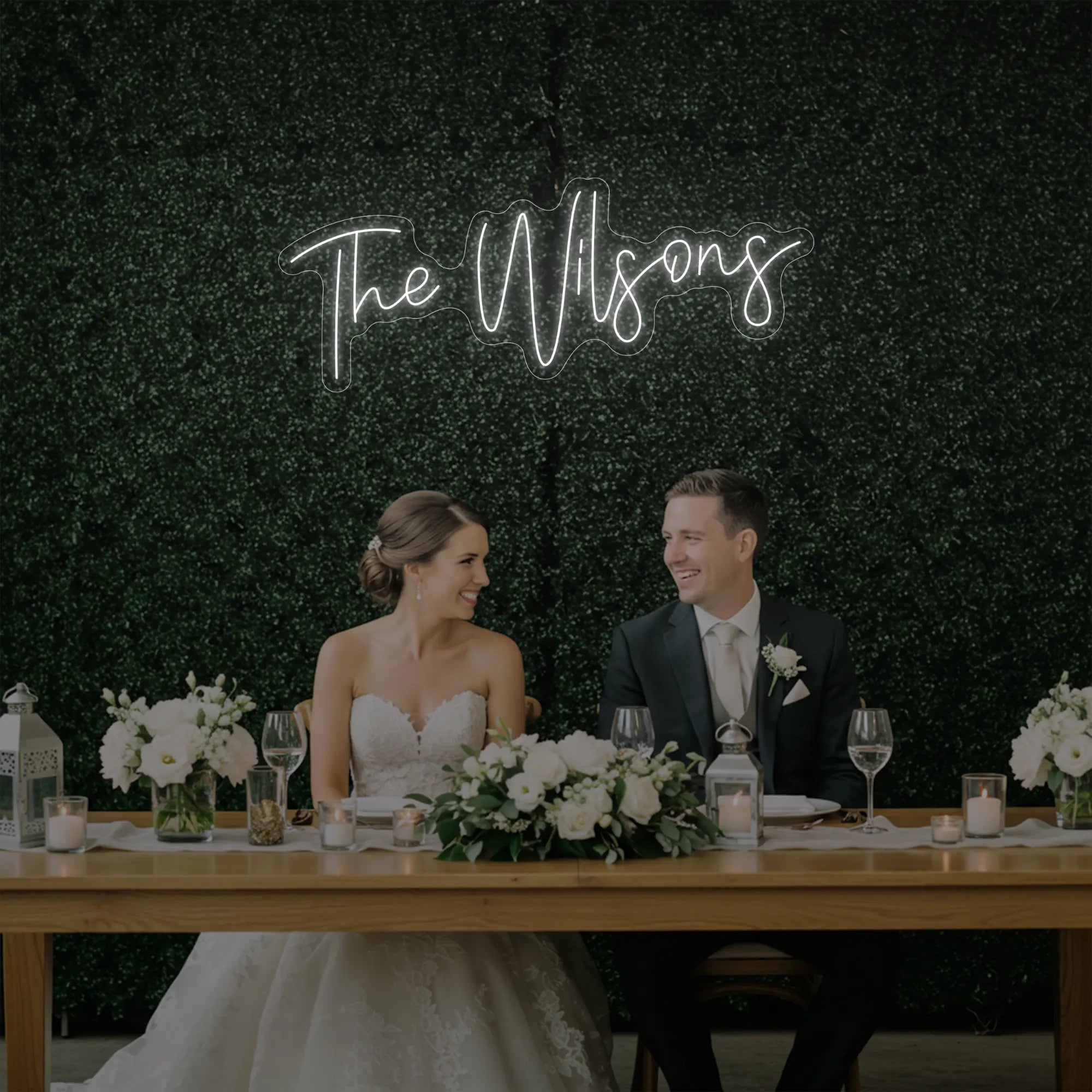 Photo of the 'Wedding Last Names Custom Neon Sign V4' neon sign glowing in cool white against a styled interior wall.