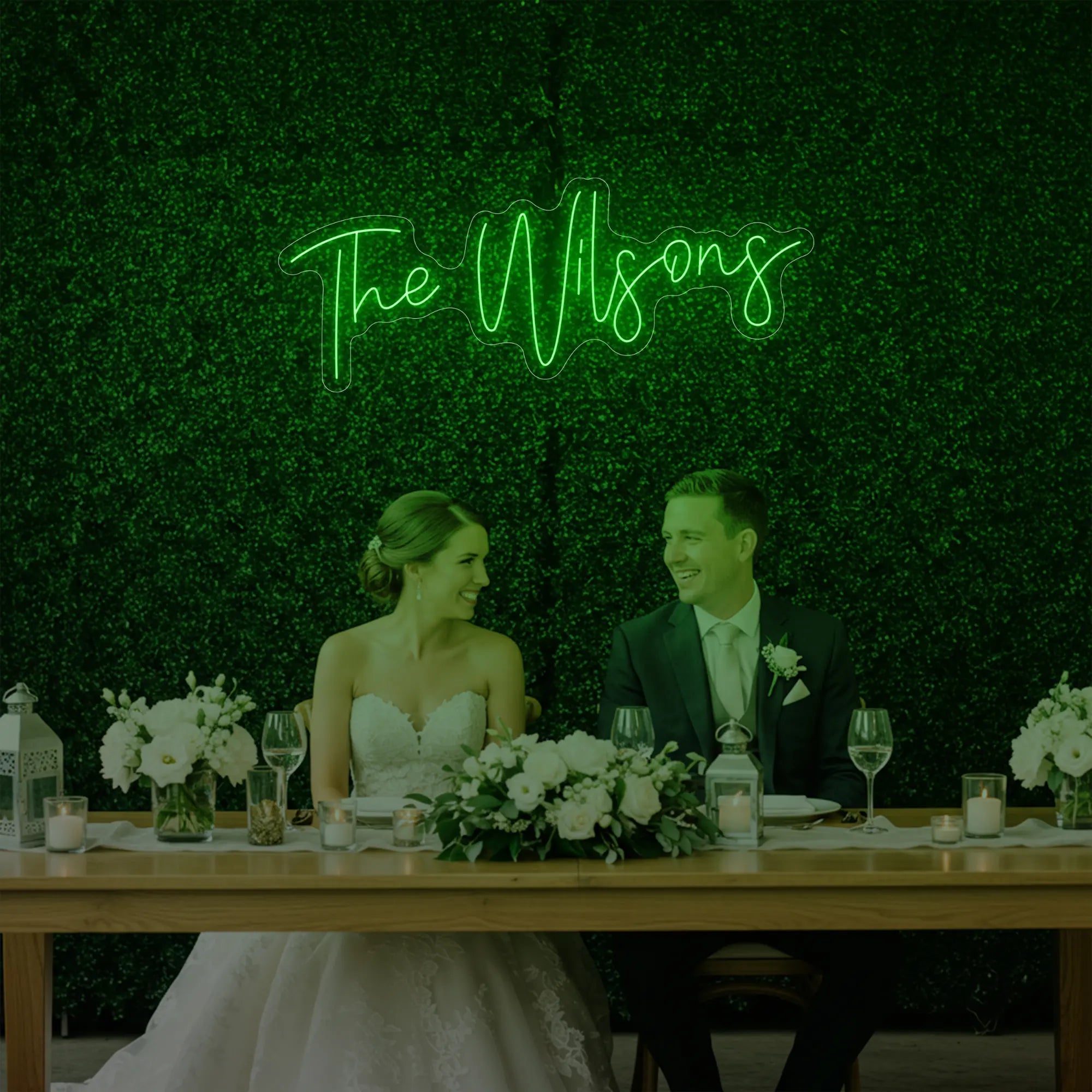 Photo of the 'Wedding Last Names Custom Neon Sign V4' neon sign glowing in green against a styled interior wall.
