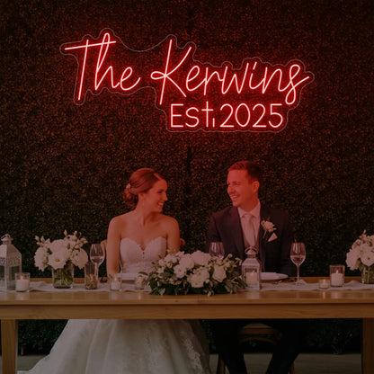 Photo of the 'Wedding Last Names Custom Neon Sign V5' neon sign glowing in red against a styled interior wall.