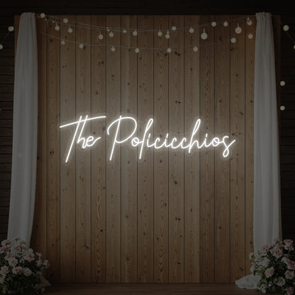 Photo of the 'Wedding Last Names Custom Neon Sign V7' neon sign glowing in cool white against a styled interior wall.