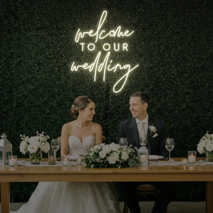  'Welcome To Our Wedding' neon sign glowing in warm white against a styled interior wall.