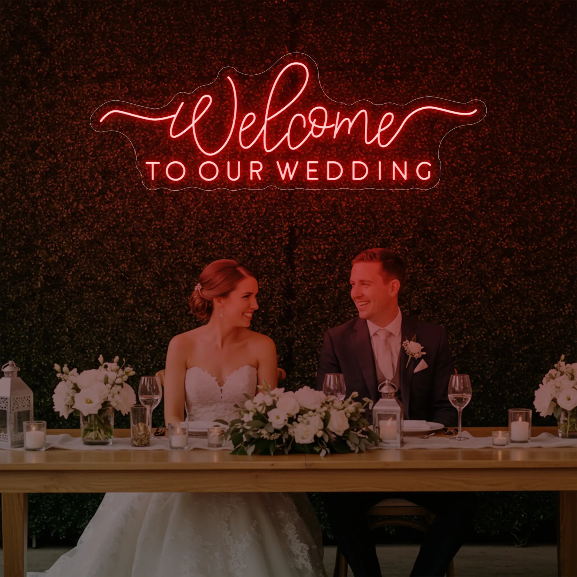  'Welcome To Our Wedding' neon sign glowing in red against a styled interior wall.
