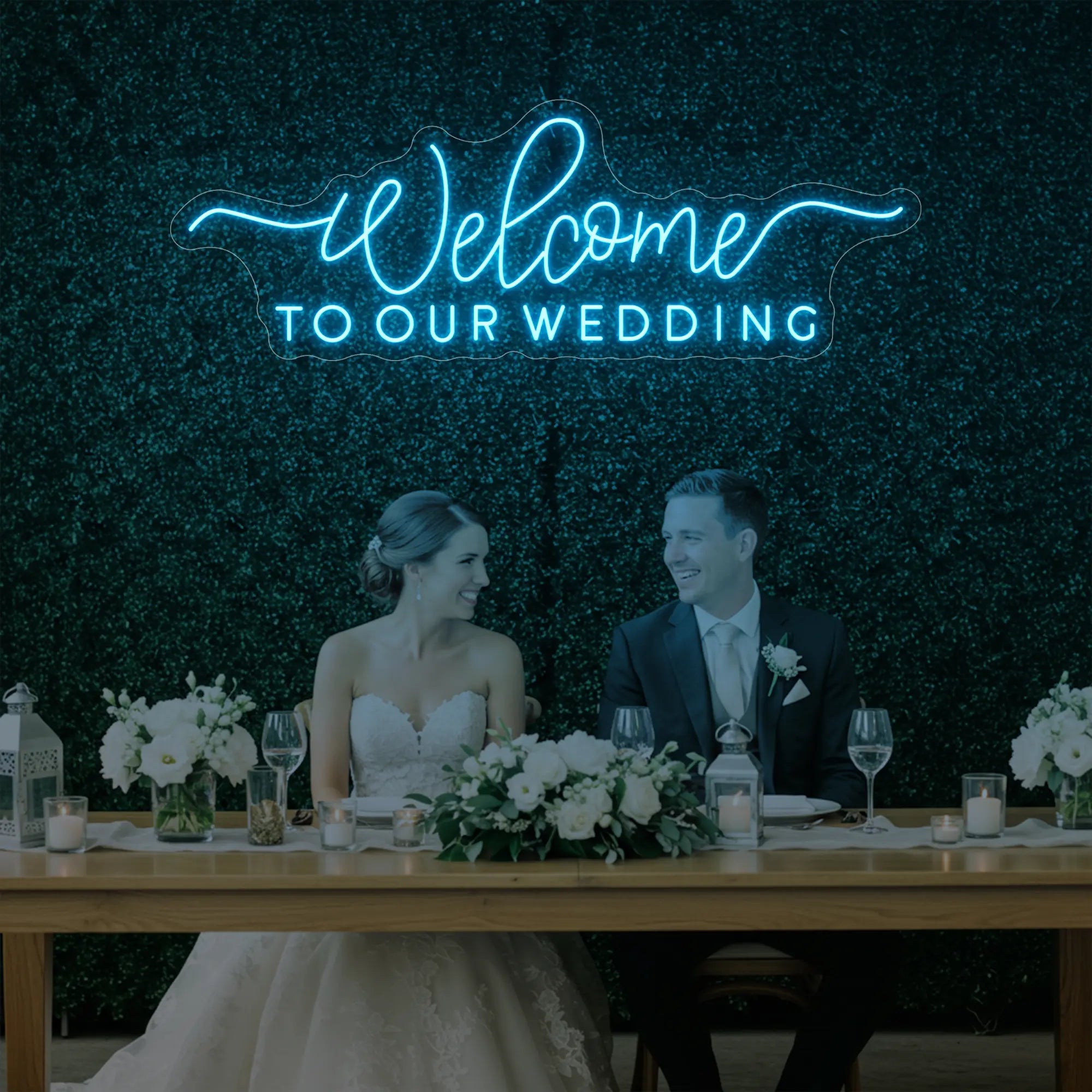  'Welcome To Our Wedding' neon sign glowing in ice blue against a styled interior wall.