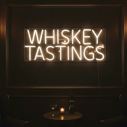 Photo of the 'Whiskey Tastings' neon sign glowing in warm white against a whiskey lounge-inspired wall.