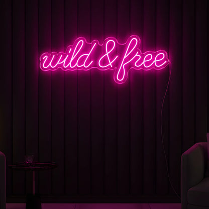 Photo of the 'Wild & Free' neon sign glowing in pink against a modern boho-inspired wall.