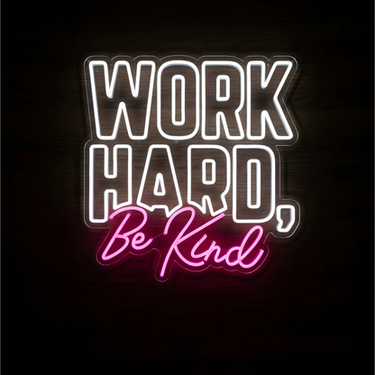 “WORK HARD, Be Kind” LED Neon Sign with white block lettering and pink script on clear acrylic backing against a dark wood background, suitable for offices, classrooms, and shared workspaces.